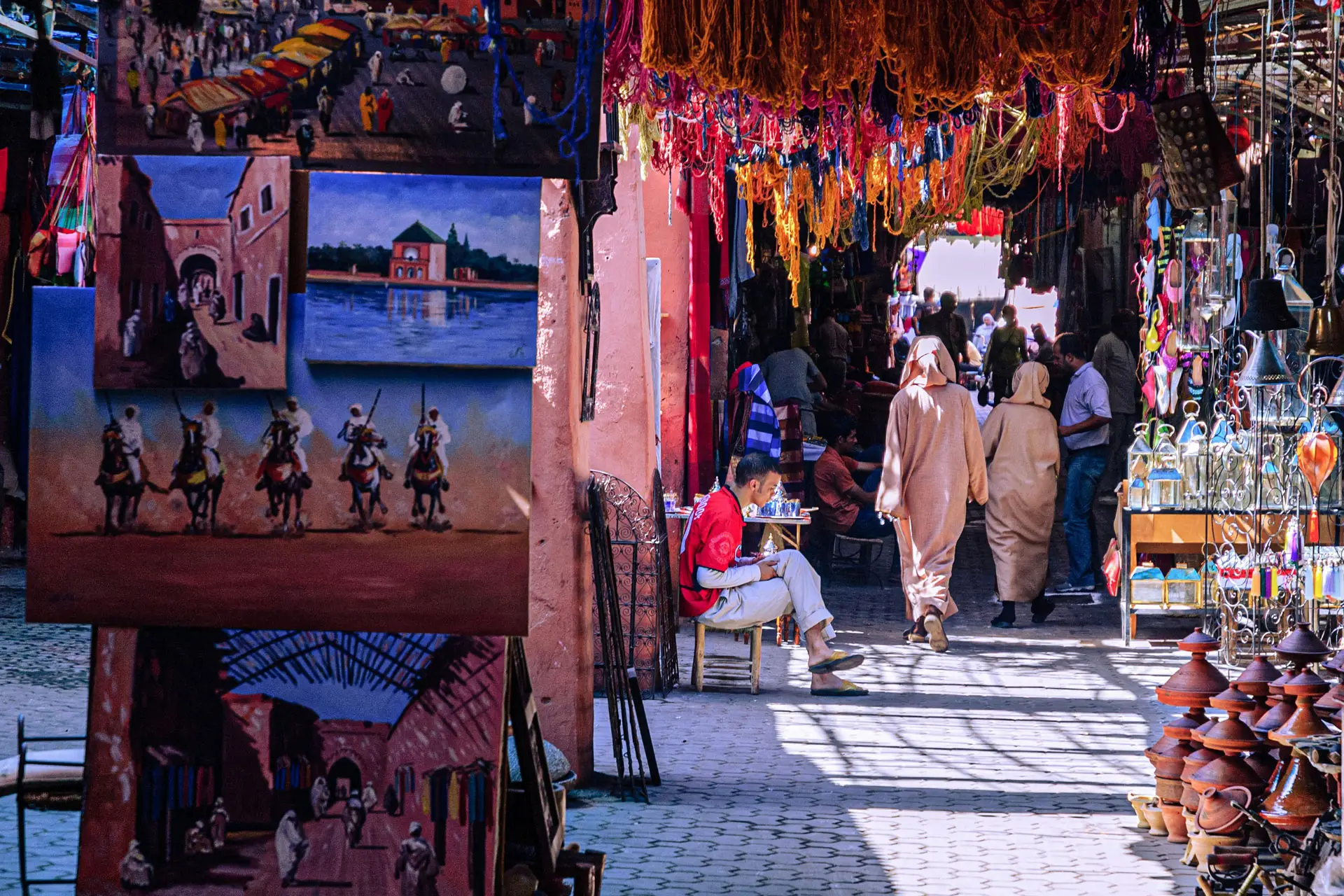 Rua do souk de Marraquexe com quadros, lãs coloridas e tajines