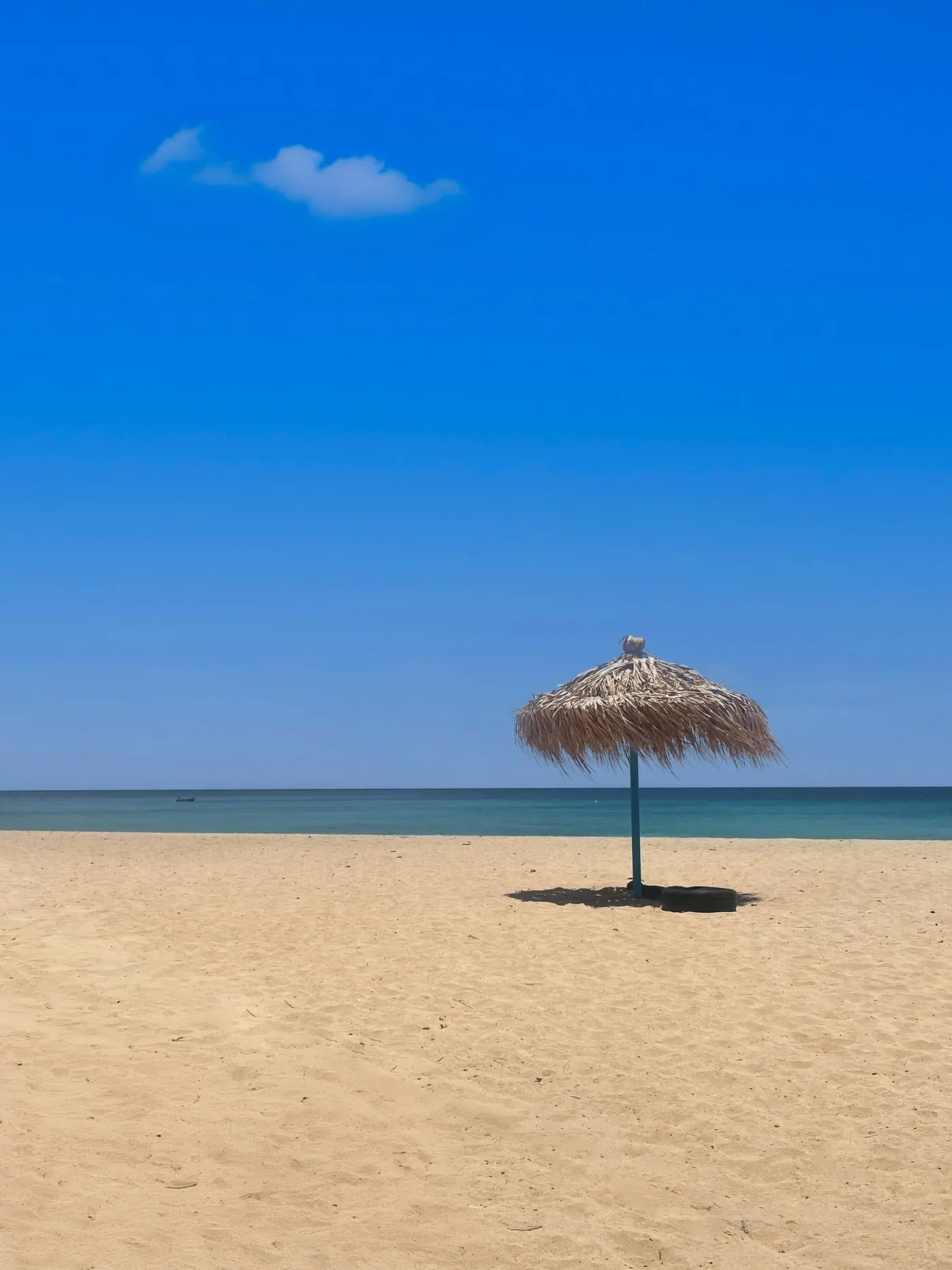 Praia de Santa Maria, com areia dourada, um guarda-sol de palha e mar azul
